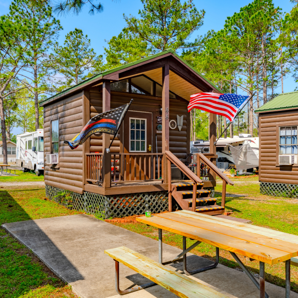 one-bedroom cabins at Lake City RV Park, in log cabin style with flags out front and a picnic table