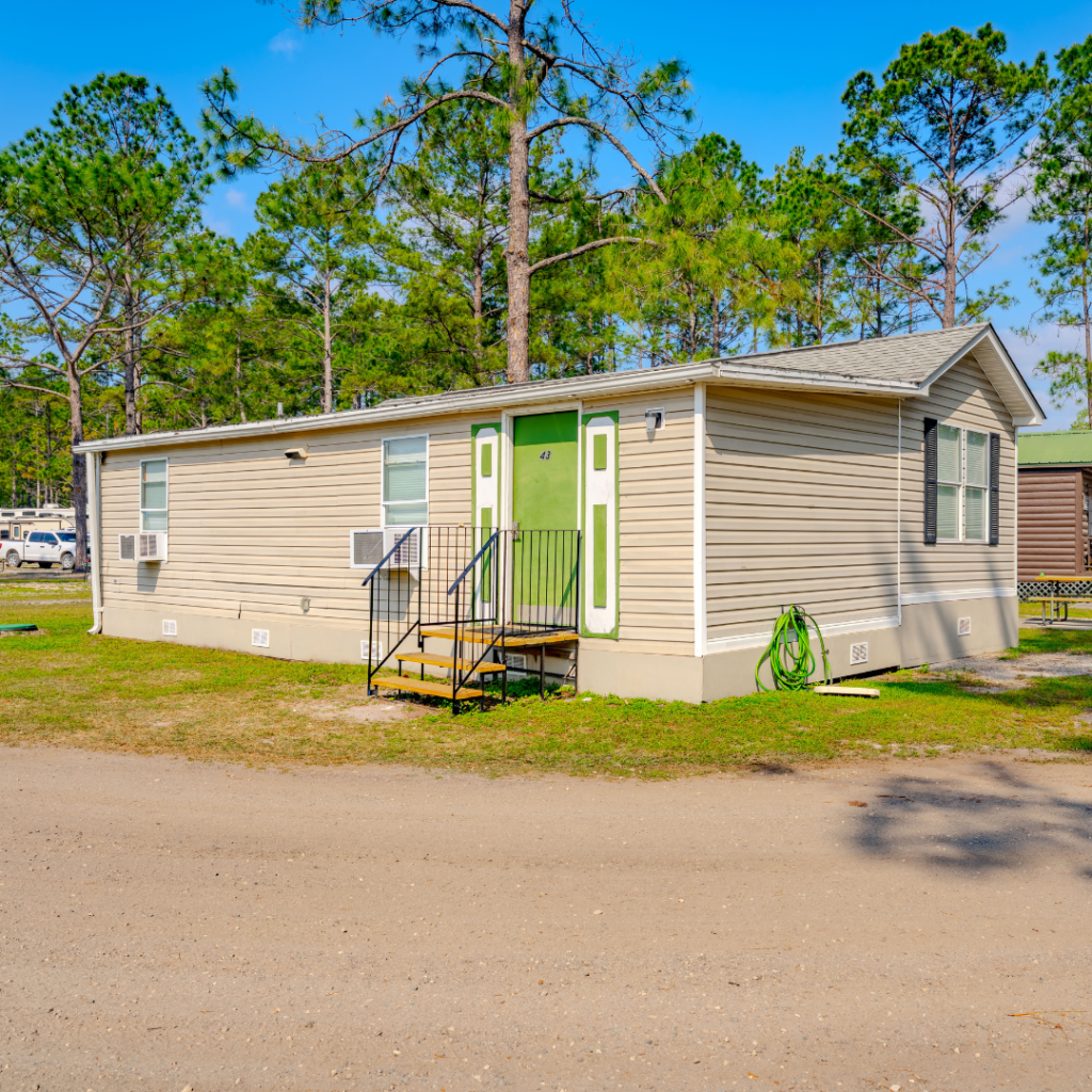 Park model for long terms stays at Lake City RV Resort, featuring a beige manufactured home with green door