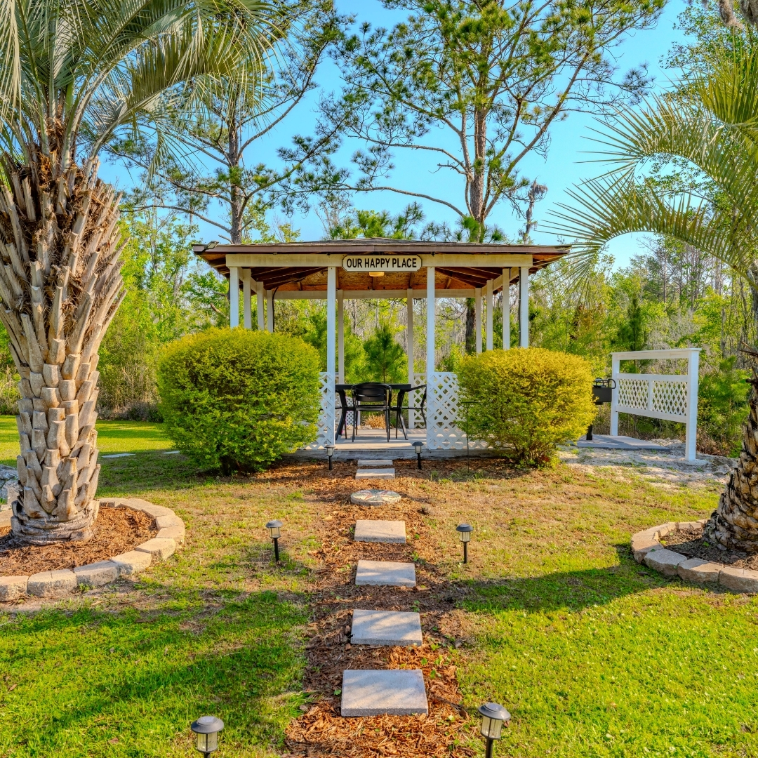Covered gazebo surrounded by pine trees and a manicured lawn
