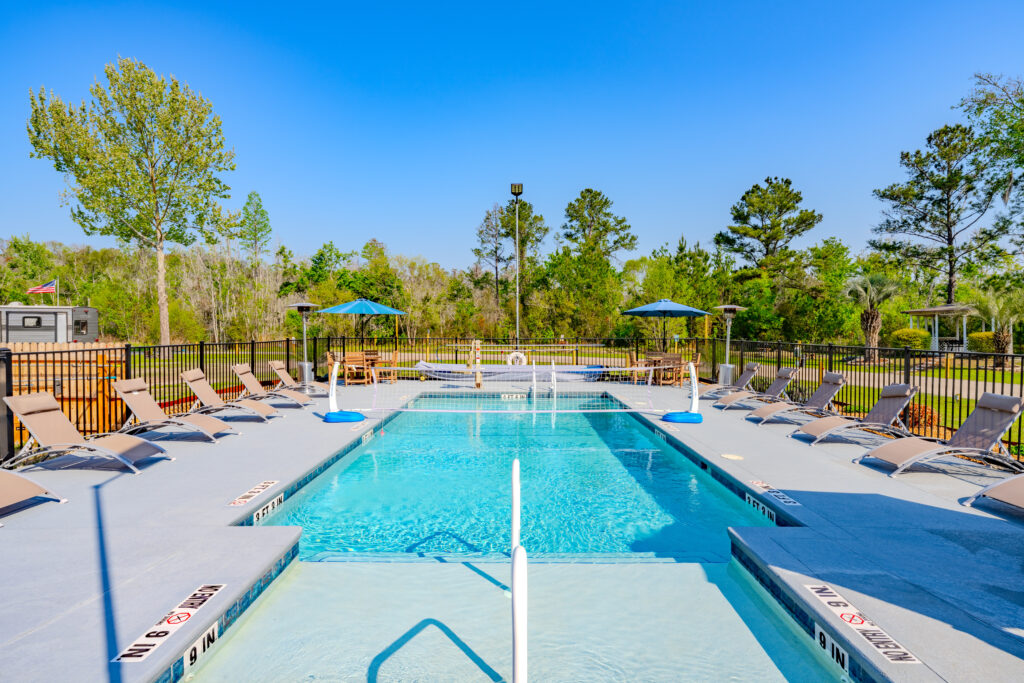 Lake City RV Resort Outdoor pool with lounge chairs on either side, on a sunny blue sky day