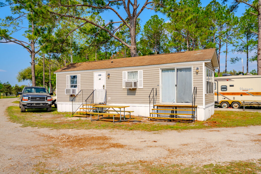 One-bedroom park model Lake City RV Resort, featuring a beige manufactured home with a white door and french sliding glass doors