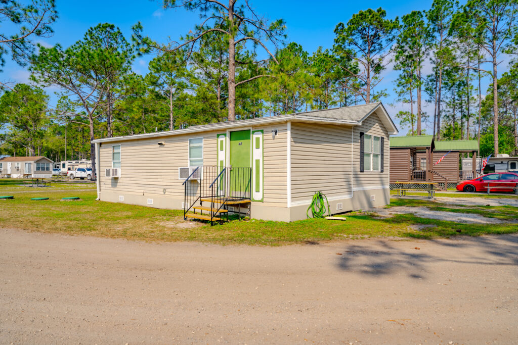 Park Model rentals at Lake City RV Resort, featuring beige manufactured home with lime green door on a sunny Florida day
