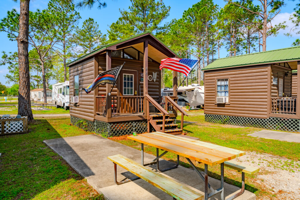 one-bedroom cabins at Lake City RV Park, in log cabin style with flags out front and a picnic table