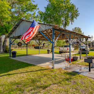 Outdoor pavilion with the United States flag waving in front, there is a grill on the right side