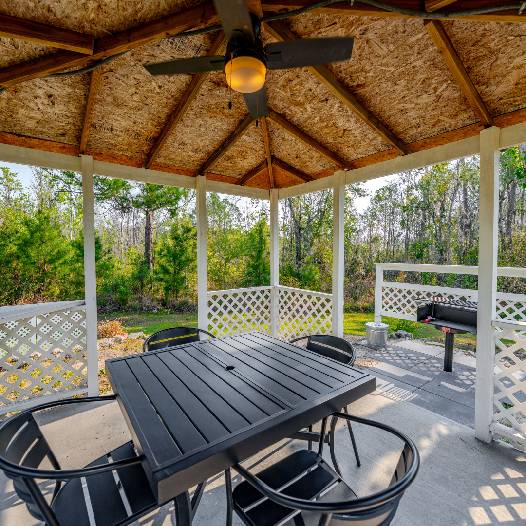 Outdoor shot of the interior of the gazebo with a square table and a grill